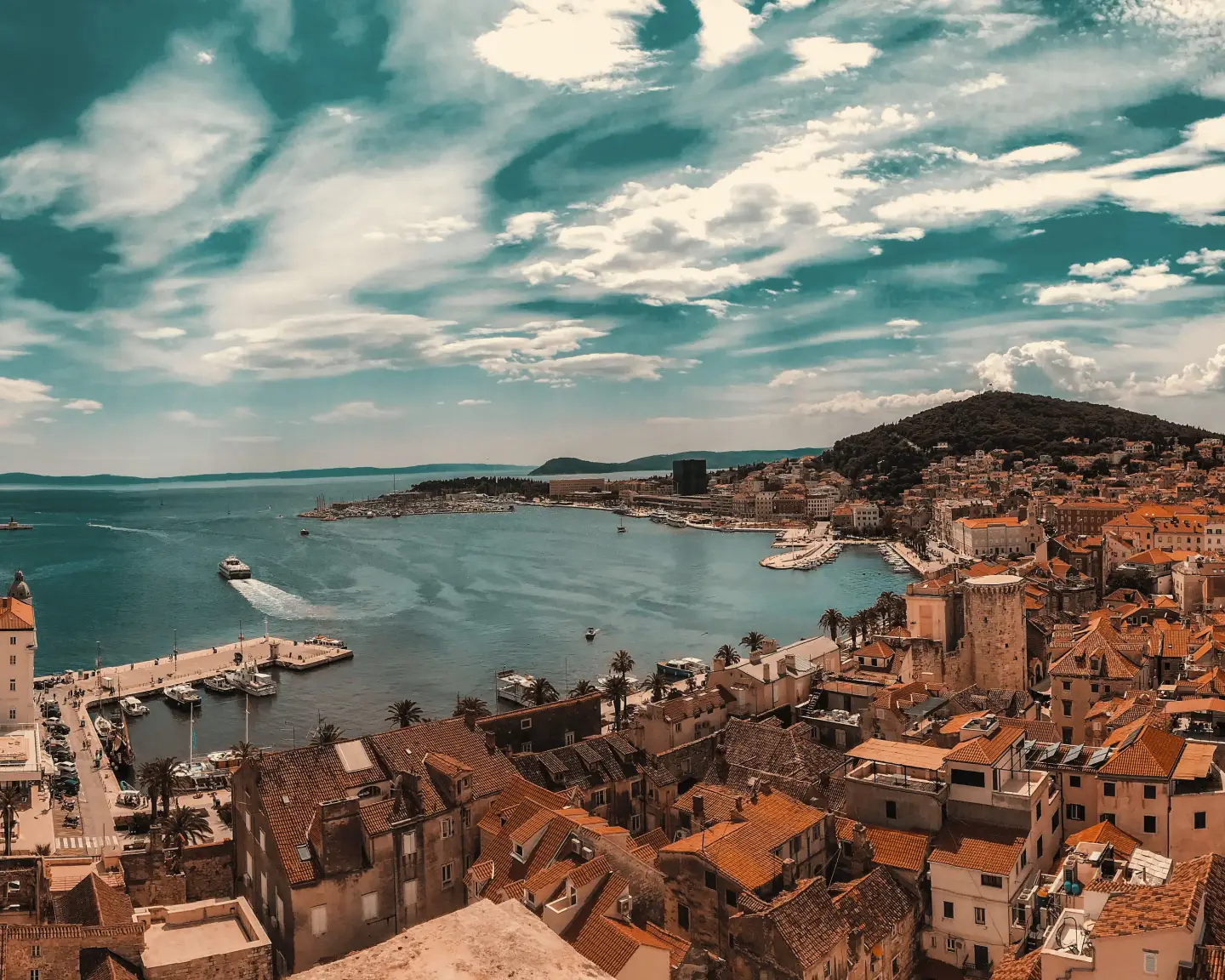 Vista panorámica del casco antiguo y el puerto de Split, Croacia, con tejados de tejas rojas, cruceros y yates a lo largo de la costa adriática bajo un cielo espectacular.