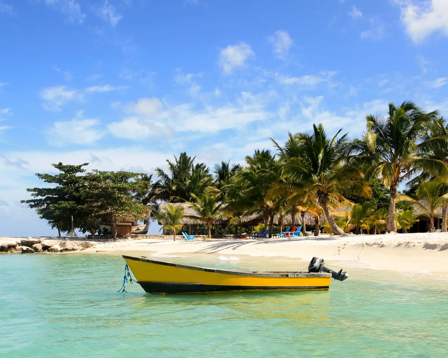 Gele boot op het strand van Bayahibe, Dominicaanse Republiek, met palmbomen en helder water.