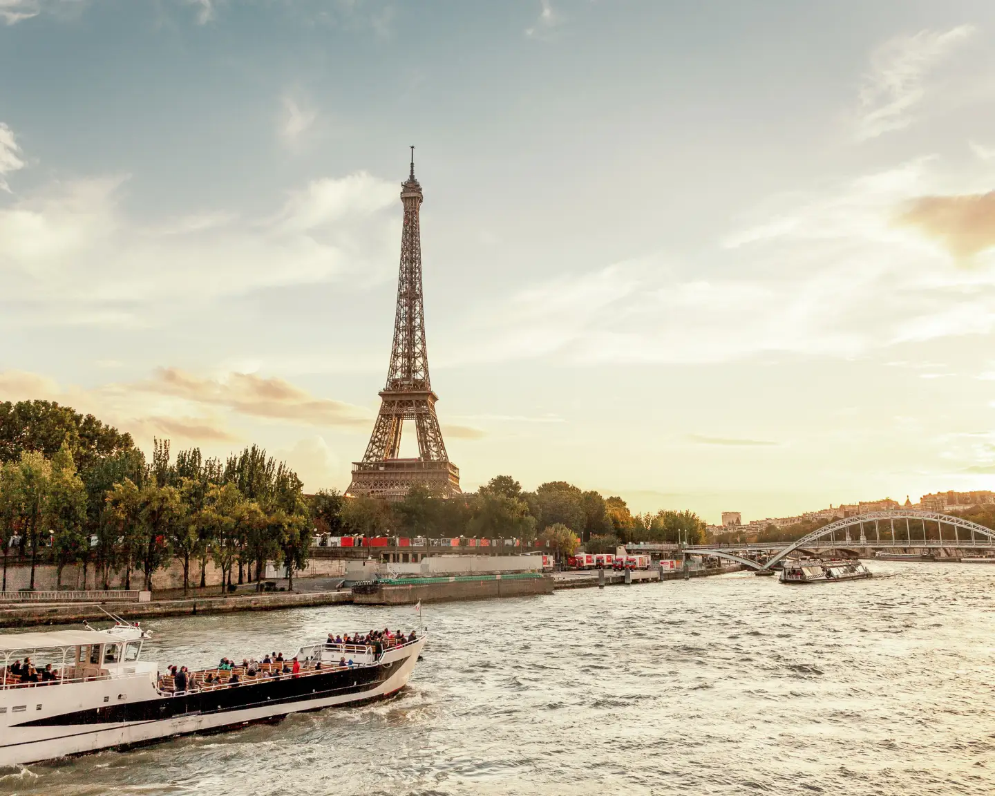 La Torre Eiffel en París con el Sena y un barco de excursiones al atardecer.