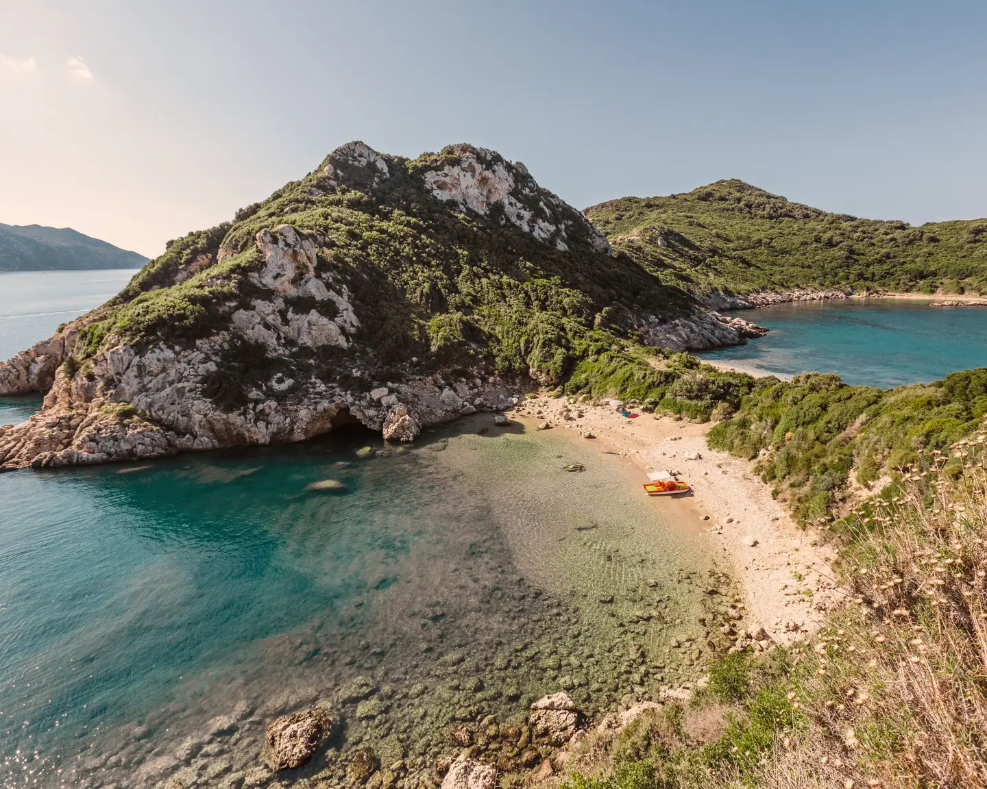 Bay in Afionas on Corfu, Greece, with a view of a mountain and beach in the sunshine.