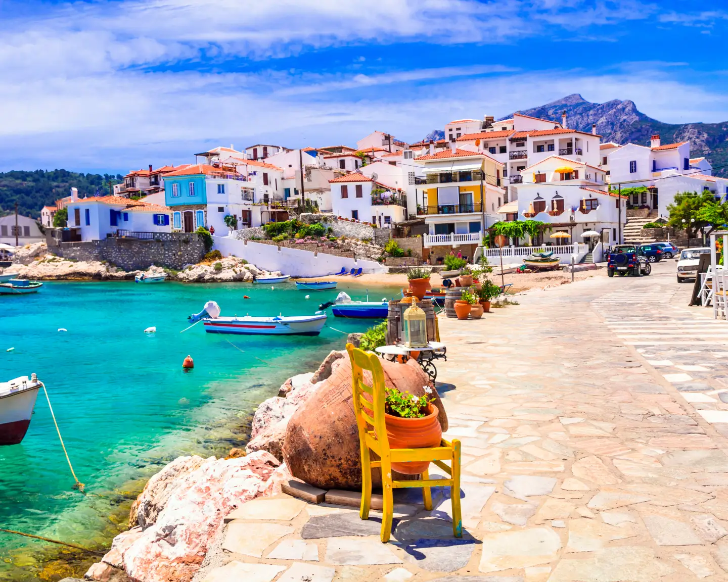 Küstenstadt Kokkari auf Samos, Griechenland, mit bunten Häusern, türkisfarbenem Meer und Fischerbooten im Hafen.