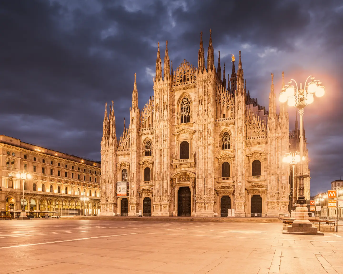 Milan Cathedral at dusk with illuminated square.
