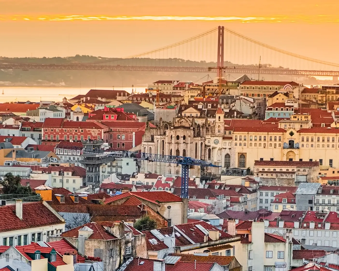 Panoramic view of the Old Town of Lisbon, the capital of Portugal, featuring the Alfama district, the Tagus River, and the April 25 Bridge in the background