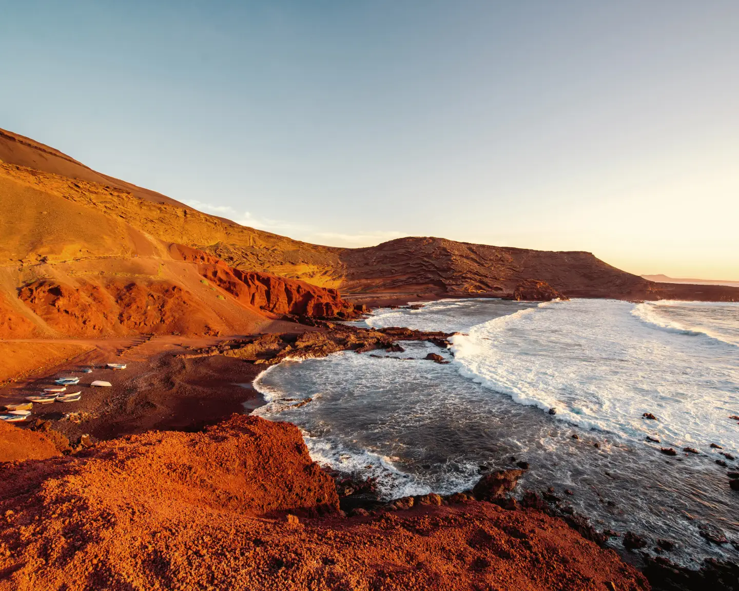 Baie d'El Golfo avec des bateaux de pêche au coucher du soleil sur l'île de Lanzarote en Espagne.