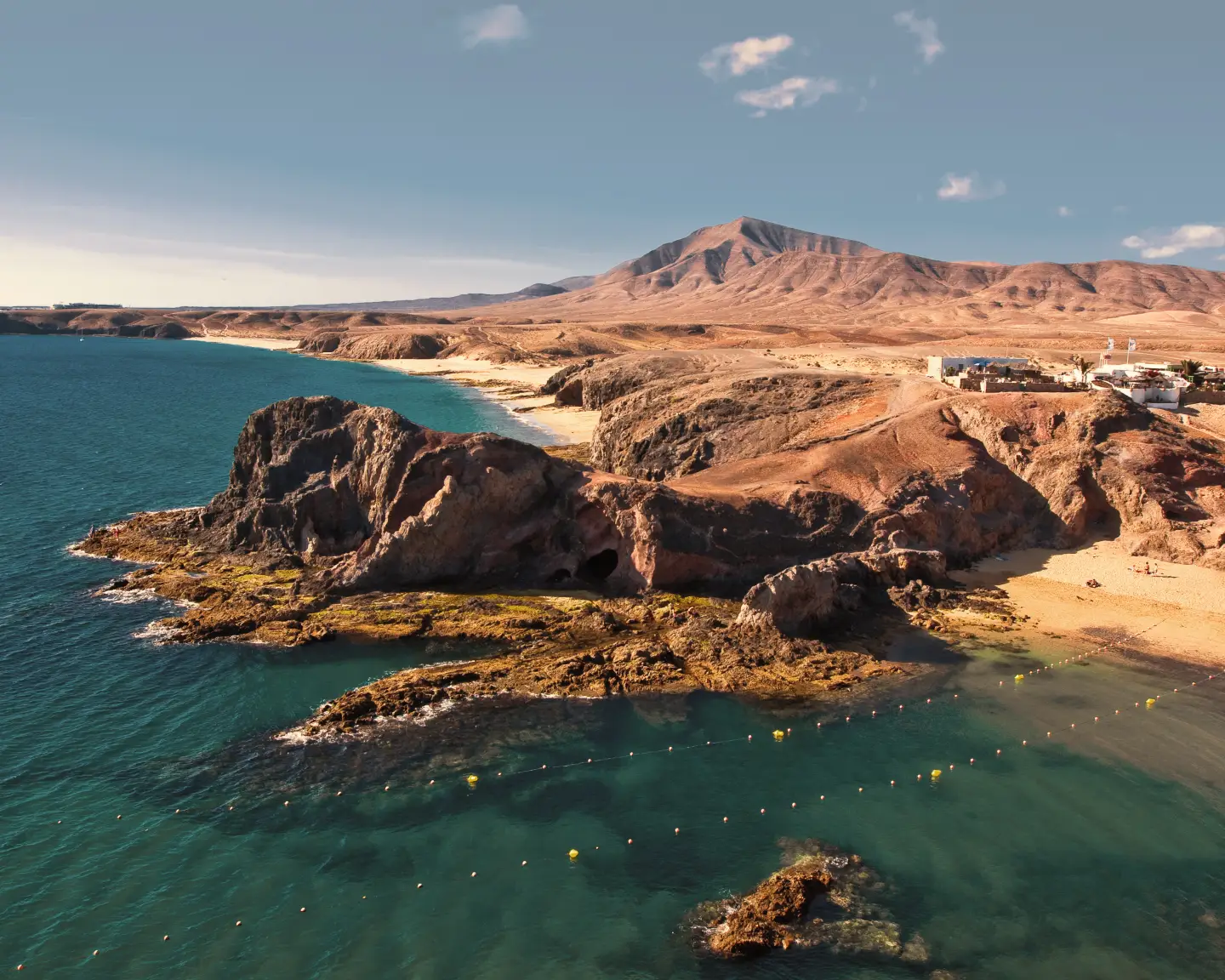 Strand op Lanzarote met uitzicht op rotsachtige kliffen en de zee