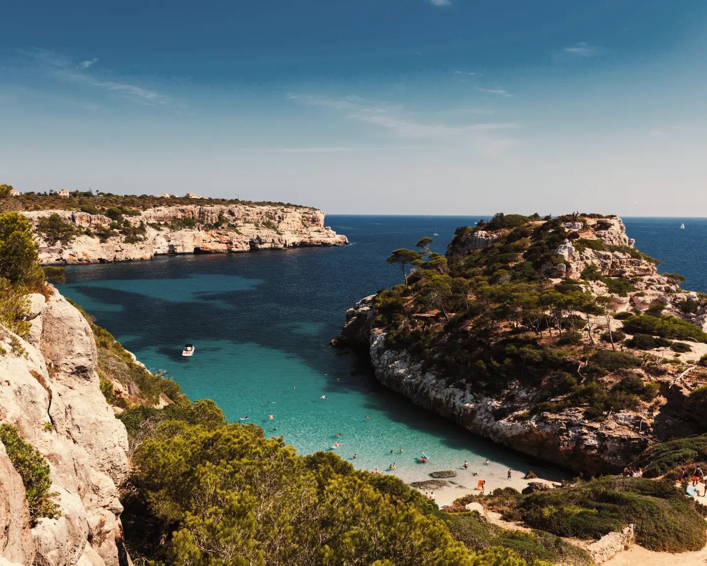 De baai Caló des Moro op Mallorca met kristalhelder water, omgeven door hoge kliffen en groene vegetatie.
