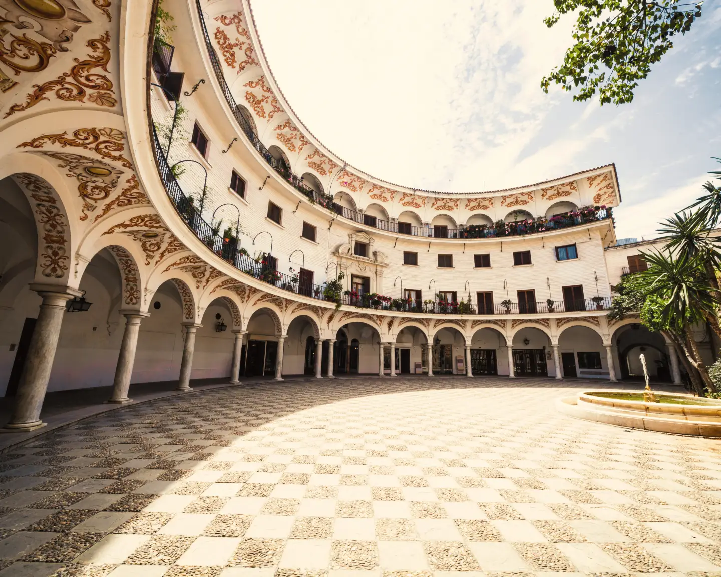 Historic courtyard in Seville, Spain, with arcades and decorative ornaments.