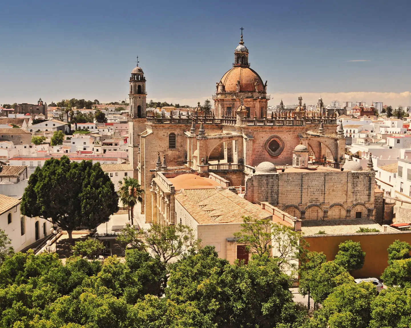 View of the cathedral of Jerez de la Frontera in Spain, surrounded by white houses and green trees.