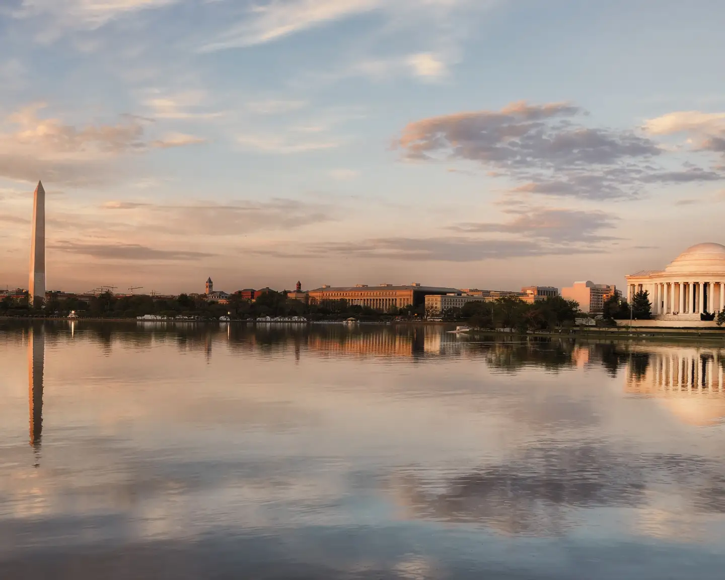 Vista del Monumento a Washington y el Monumento a Jefferson al atardecer, reflejados en el agua de la Cuenca Tidal en Washington, D. C.